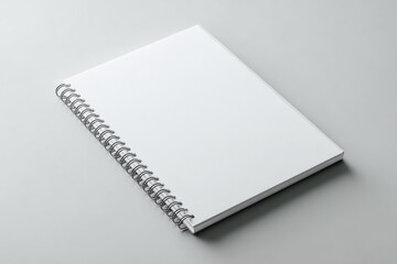 A blank, white spiral-bound notebook rests on a light gray surface, showcasing its clean, minimalist design and unblemished pages