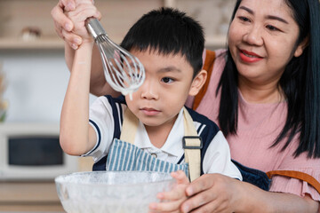 Family Bonding in the Kitchen. A mother guiding her son as they whisk batter together.