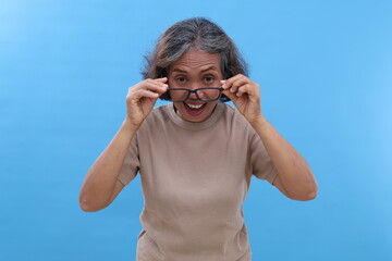 Asian old woman with grey hair, wearing glasses, standing looking at camera looking happy, gesture...