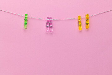 Colorful clothespins hanging on a line against a pink background creating a cheerful and vibrant atmosphere indoors