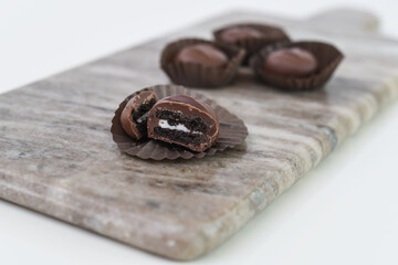 Decadent Chocolate Covered Sandwich Cookies on grey Slate chocolate coating contrasts beautifully with the smooth white cream filling side view of sweet dessert