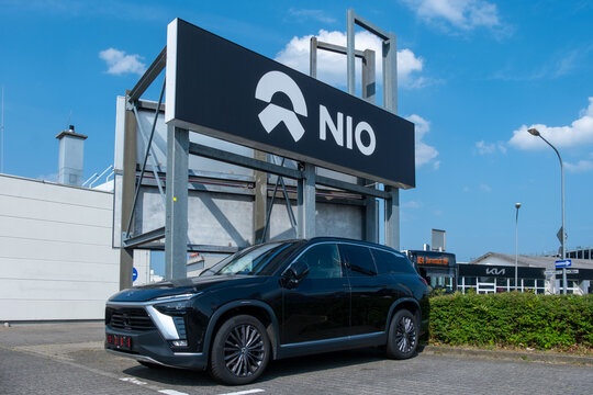 premium Chinese NIO ES8 electric car at service center, corporate NIO logo against blue sky, electric vehicle market, sustainable and high-tech mobility innovation, Germany