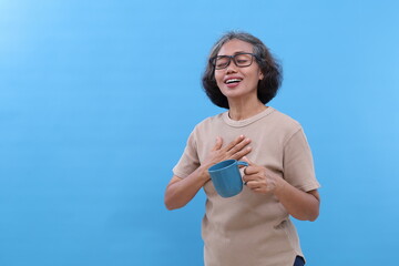 Asian old woman with gray hair smiling holding chest and holding drinking glass, closing eyes,...
