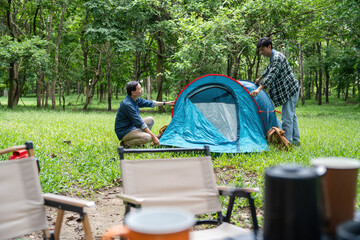 Setting up camp. Father and son assembling a tent together in the forest.