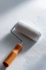 Fototapeta premium Paint roller with wooden handle on white surface in sunlight