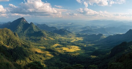 Obraz premium Panoramic vista of a verdant valley nestled amongst majestic, sun-dappled mountains under a partly cloudy sky
