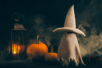 Halloween ghost doll with witch hat and pumpkins, spooky lantern and fog, autumn holiday decoration – festive Halloween or autumn concept.