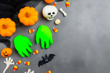 Halloween pumpkins, skull, green monster hands, and candy on gray table, playful spooky atmosphere – seasonal holiday party and decoration concept.