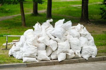 Waste material stacked in white bags in a park area during daytime