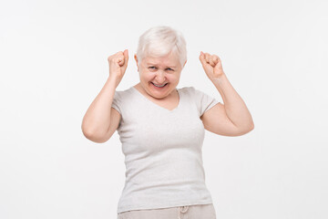 Portrait of healthy cheerful senior elderly woman smiling and raising fists in isolated white background studio shot, health care, insurance and happy retirement concept