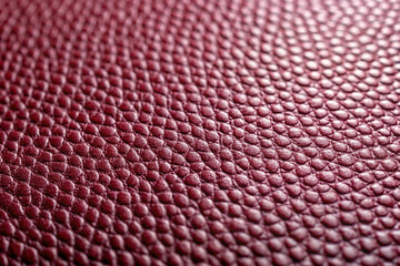 Close up view of a textured burgundy leather surface with a repeating pattern and subtle highlights