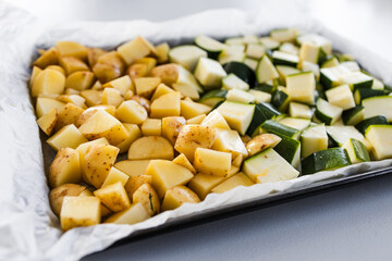 oven tray with cubed baby potatoes and zucchini ready for roasting