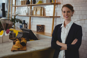 Female staff in blazer organizing pastries on marble counter at cafe using POS terminal, copy space