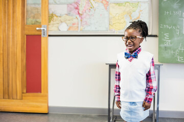 Fototapeta premium Wooden door with red panel featuring world map on classroom wall, chalkboard showing equations