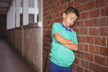 Boy leaning against red brick wall and white railing with arms crossed in corridor, copy space