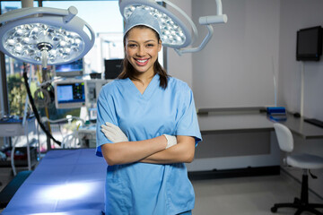 Female surgical nurse in scrubs standing in operating room at head of table under LED lights