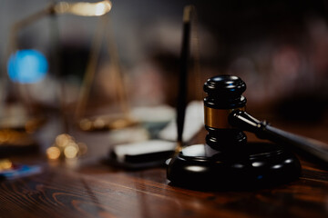 Black gavel and golden balance scale on wooden desk, representing justice, law, financial...