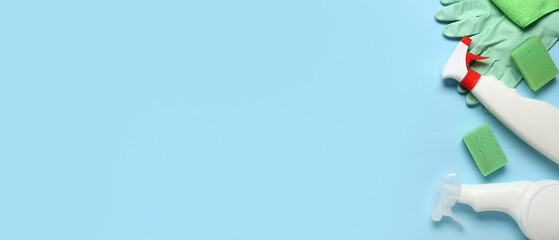 Set of cleaning supplies and bottle of detergent on blue background