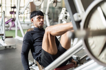 Leg Press Workout. Young man focusing on leg press exercise in a gym.
