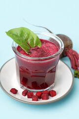 Plate with glass of healthy beet juice and spinach on blue background