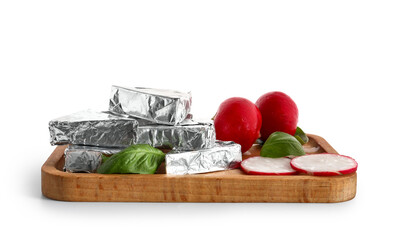 Board with triangles of tasty processed cheese in foil, radish and basil leaves on white background