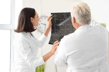 Obraz premium Doctors examining x-ray scan in medical office, back view