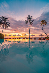 Beautiful sunset at luxury infinity pool resort palm trees umbrellas reflecting tranquil water...