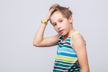 Young boy poses stylishly against a neutral background showcasing playful expression and casual...