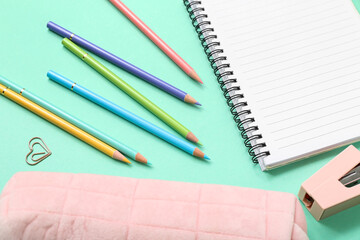 Many colorful pencils with stationery on turquoise background
