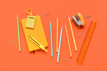 Colorful pencils with stationery on orange background