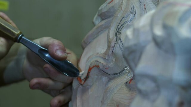 Extreme close up of Professional sculptor hands carefully carving intricate wooden sculpture with traditional gouge, revealing detailed craftsmanship in precise slow motion technique