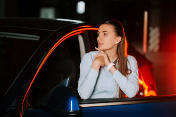 Woman looking thoughtfully out of a car window at night in an urban setting