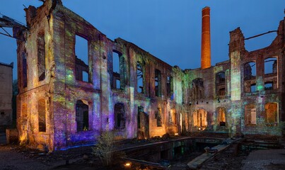 Vibrant projections illuminate abandoned factory at dusk