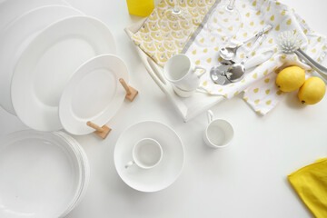 Set of white dishes with cleaning supplies and lemons on table, top view