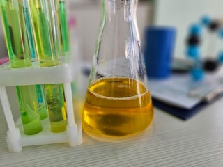 Scientist performs chemical analysis with yellow liquid in laboratory setting near blue canister