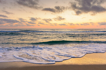 sea wave touch the sand beach at dawn. summer vacations in sozopol. nature after tranquil dream under glowing orange sky with dark clouds. scenic view of a seascape with calm water and relax mood