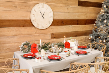 Dining table with beautiful setting for Christmas celebration near wooden wall