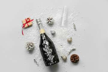 Bottle of champagne with glass, Christmas balls and cones on white background