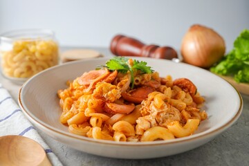 Stir fried macaroni with tomato sauce ,sausage and egg in white plate on grey background