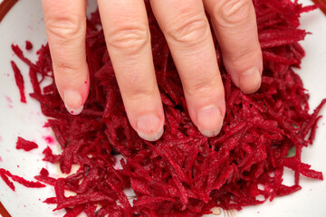Shredding vibrant beets in a rustic kitchen at midday