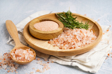 Wooden plate and spoon of Himalayan pink salt with rosemary on white background