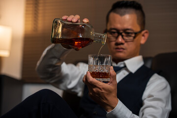 Businessman holding a glass of whiskey and drinking on a sofa.