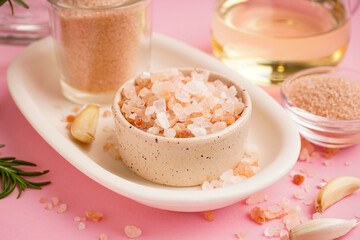 Bowls with Himalayan pink salt and garlic on pink background