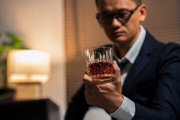 Businessman holding a glass of whiskey and drinking on a sofa.