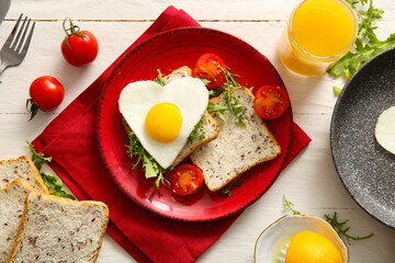 Composition with tasty fried egg, tomatoes, toasts in plate and glass of juice on light wooden background