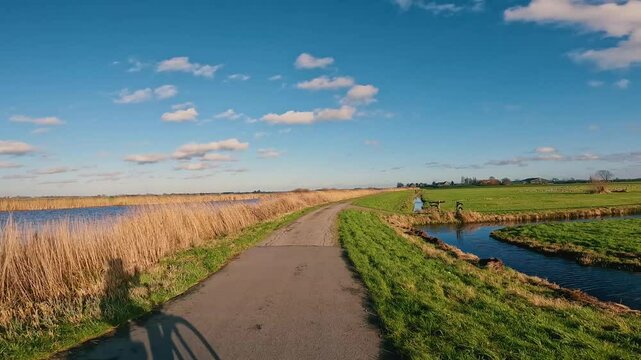 4k cinematic footage of a country path that runs along the famous water canals in the Netherlands. A typical Dutch road that can be cycled or walked at the end of the day.