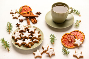Composition with delicious stars shaped Christmas cookies, cup of tea, spices and fir tree branches on light background, closeup