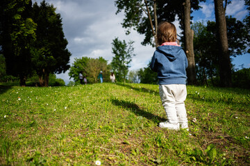 Child exploring a sunny park surrounded by trees and greenery