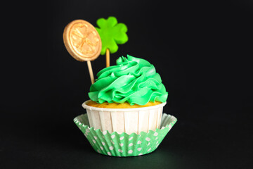 Tasty green cupcake for St. Patrick's Day on black background