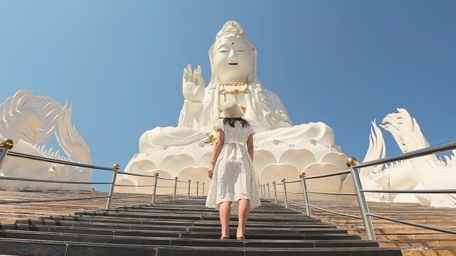 Tourist woman walking near white dragon staircase at Wat Huay Pla Kang Chiang Rai Thailand. Buddhist spiritual site, travel experience, cultural tourism, spiritual journey, religious architecture